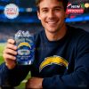 A fan shows off the Los Angeles Chargers 65th Anniversary glass while dressed in team gear, blending fashion and football celebration!