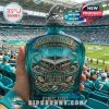 A Miami Dolphins fan holding the 60th Anniversary whiskey decanter at the stadium, showing the design with the football game in the background.