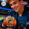 A man looks closely at a Miami Marlins whiskey glass shaped like a baseball. The logo and golden stadium art are visible, with the collector box placed next to him!