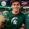 Young fan in green shirt enjoys Michigan State University 170th Anniversary glass at sports event.