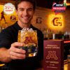 A person holding the Minnesota Golden Gophers whiskey glass filled with ice, featuring the team’s logo and anniversary engraving.