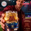 A person enjoying the Minnesota Golden Gophers whiskey glass with ice, set against a stadium backdrop with a celebratory feel.