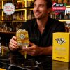 A man presents a Nashville Predators whiskey glass with golden drink and detailed design while seated at a polished bar counter!