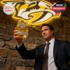 A Nashville Predators supporter holds a golden whiskey glass high with the team logo shining behind him!