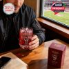 Man holding NC State Wolfpack whiskey glass with red gift box beside him while sitting near a stadium window!