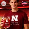 A Nebraska fan at the stadium holds a matching anniversary whiskey glass and shirt, proudly displaying team spirit and celebration!