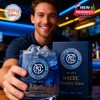 A man at a bar holds a blue whiskey glass with NYCFC branding. The golden New York skyline and collector box are clearly visible on the table!