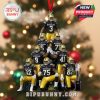 Football ornament with Notre Dame players dressed in blue and gold forming a pyramid pose. It includes a red ribbon for hanging, a gold helmet design, and a trophy at the base. Tree lights and holiday decorations create a warm background!