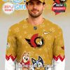 A man posing in a gold hockey jersey decorated with cartoon dog images, Ottawa Senators insignia, and colorful sleeve details.
