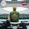 A Green Bay Packers fan holding the 105th Anniversary whiskey decanter with Lambeau Field in the background.