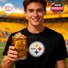 A man in a black Steelers t-shirt holds a whiskey glass filled with ice and a dark drink. The yellow towel and stadium engraving are shown clearly with the stadium behind!