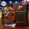 Purdue Boilermakers whiskey glass with engraved stadium and crest in front of dark wood style collector box marked with founding year and motto.
