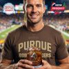 Fan in brown Purdue Boilermakers shirt holding commemorative whiskey glass at a live game with the field in the background.