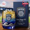 San Diego FC whiskey glass with ocean blue base and gold drink displayed next to a branded gift box in a football stadium!