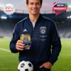 Man smiling while holding a San Diego FC whiskey glass in a stadium with green field in the background!