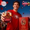 Happy 49ers fan celebrating at the stadium with the commemorative glass raised high next to its collector’s box!