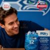Candid shot of a man leaning in to appreciate his Seahawks glass, with deep blue hues and collectible packaging highlighted in the background!