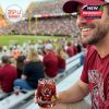 A Gamecocks supporter enjoys a drink from a branded whiskey glass while attending a match, surrounded by fans in the stands.
