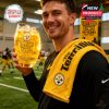 Steelers-themed practice setting where supporter poses with golden football-shaped whiskey glass and towel, celebrating 50 years of tradition!