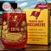 A Tampa Bay Buccaneers themed whiskey glass with rich red tones and detailed artwork is placed next to a matching yellow box!