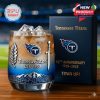 Commemorative glass with Tennessee Titans logo and sword design filled with ice beside a matching anniversary gift box on a wooden table in a stadium!