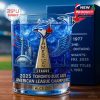 Close-up of a whiskey glass celebrating the 2025 ALCS win by the Toronto Blue Jays, with detailed engravings and vivid blue coloring.