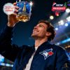 Man in stadium celebrating with raised 2025 Blue Jays championship whiskey glass under stadium lights.