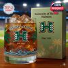 A whiskey glass celebrating the University of Hawaii features vivid tropical and volcanic motifs, presented with its collectible gift packaging.