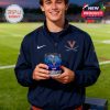 Young male fan in UVA jacket holding a branded whiskey glass filled with blue liquid on the field at dusk, showing school pride and team spirit!