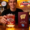 Man in casual attire at a bar holding a red University of Wisconsin Badgers glass with ice and drink, sitting beside a branded gift box!