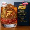 The USPS 250th Anniversary whiskey glass filled with ice, highlighting the intricate design with a delivery truck, Capitol building, and postal worker in gold on a rich background.
