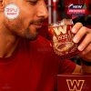 A man raises a glass with detailed Commanders engravings, including the Capitol and stadium, surrounded by a deep red drink and reflective gold finish!