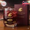 A detailed view of a premium whiskey glass designed for the 131st anniversary of Washington State University, with rich maroon and gold branding, sitting on a wood surface with a matching maroon box!