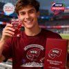 Young man dressed in red WKU gear holds a branded glass filled with red drink and a box with anniversary markings, standing in a packed sports venue!