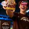 A cheerful fan at the stadium lifts a Western Michigan Broncos whiskey glass featuring anniversary design details.
