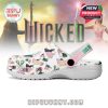 A colorful fantasy-style Crocs shoe with the Changed For Good strap and scattered Wicked icons, presented in front of magical figures from the story!