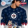 Front detail of the Bluey x Jets jersey with vibrant character artwork and team logo against a navy and white background with red sleeve accents!