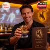 Fan holding Wyoming Cowboys whiskey glass in a bar environment highlighting the engraved cowboy scene and gift packaging!