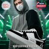 A person standing in front of a concert stage while wearing black and white Alan Walker sneakers.