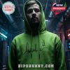 A person wearing a green hoodie with a signature in an industrial environment.