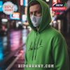 A person wearing a green hoodie with Alan Walker's signature in a city at night.