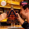 Two Auburn Tigers fans toasting with the Auburn Whiskey Bottle at the bar, featuring the iconic logo and a golden crown on top.