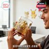 A man admires a Dragonite Pokemon 30th Anniversary whiskey glass with gold embossing in a clean office environment!