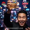 A man cheerfully holds a Pokémon 30th Anniversary glass in front of a vibrant night city view!