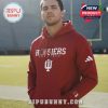 Man wearing red Hoosiers Football hoodie seated in a locker room with a football.