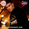 A man wearing a black Iowa Hawkeyes Champions 2025 zip hoodie, captured in a warm evening city scene with golden lighting!