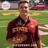 Man in Iowa State jacket holding a Cyclones bottle while sitting in an empty football stadium at night.