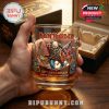 Hand holding an Iron Maiden commemorative whiskey glass with detailed band artwork and golden drink inside!