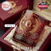 Close-up of Style 1 Manchester United glass in red and gold, resting in a satin-lined collectible box for the 148th anniversary edition.