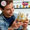 A happy man holding a gold-embossed Pokémon whiskey glass with Mewtwo design, standing near a display of Pokémon figures!